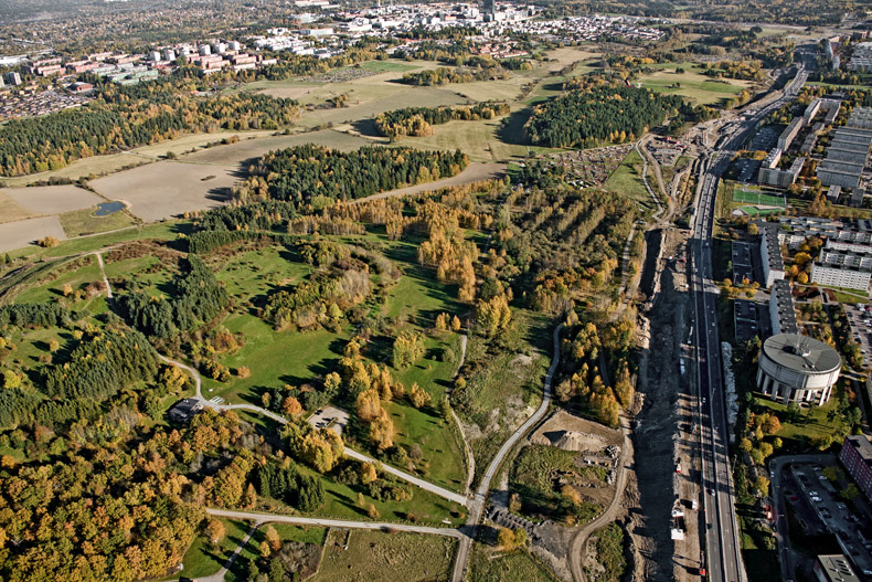 Östra delen av Järvafältet med E18 och Hjulsta vattentorn till höger. I bakgrunden syns bland annat Kista.